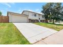 Spacious home with a long driveway, attached garage, and lush green lawn on a sunny day at 6994 W Hinsdale Dr, Littleton, CO 80128