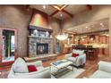 Cozy living room showcasing stone fireplace, exposed beams and a view into the adjacent kitchen at 4691 Bandera Pl, Parker, CO 80134