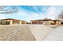 Expansive home featuring a long driveway leading to multiple garages, set against a blue sky at 3299 S Newcombe St, Lakewood, CO 80227