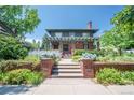 Charming two-story home with brickwork and wood pergola, steps lead to front door surrounded by flower beds at 171 N Franklin St, Denver, CO 80218
