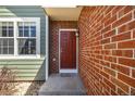 Inviting entryway with a classic red door, brick facade, and a charming sconce for a warm welcome at 4252 S Halifax Way, Aurora, CO 80013