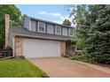 Two-story home with a large garage and driveway, brick accents, and beautiful blue siding at 9963 W Canyon Ave, Littleton, CO 80127
