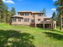 The back of this home features a large yard and covered patio at 7197 Timbers Dr, Evergreen, CO 80439