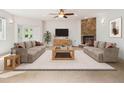 Cozy living room featuring a stone fireplace, ceiling fan, and two comfortable sofas at 7197 Timbers Dr, Evergreen, CO 80439