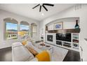 Cozy living room with a fireplace, arched windows, and comfortable seating with bright accents at 15156 W Baker Pl, Lakewood, CO 80228