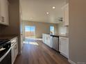 Modern kitchen with stainless dishwasher, ample countertops, and hardwood-style floors that flow to the backyard access at 48280 Shetland Dr, Bennett, CO 80102