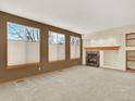 Spacious living room with large windows, neutral carpet, and a cozy fireplace at 6094 Terry Ln, Arvada, CO 80403