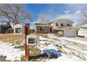 Charming home with a red front door, featuring a community book exchange on a snowy day at 4879 S Xenophon St, Morrison, CO 80465