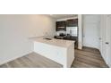 Modern kitchen featuring a breakfast bar, stainless steel appliances, and wood floors at 702 N Bently St, Watkins, CO 80137