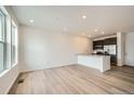 Bright living room featuring wood floors, recessed lighting, and open layout to the kitchen at 702 N Bently St, Watkins, CO 80137