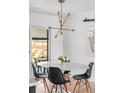 Modern dining area with stylish light fixture, white table, and sliding glass doors to the backyard at 3103 W Bellewood Dr, Englewood, CO 80110