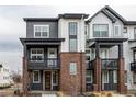 Modern townhome with gray and white siding and brick porch supports at 1342 Independence St # 6, Lakewood, CO 80215