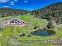 Expansive aerial view of a home with a pond, manicured lawns, and scenic mountain backdrop at 20101 Spring Gulch Rd, Morrison, CO 80465