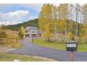 Two story home with an attached three car garage sits on a grassy lot with trees and a paved driveway at 20101 Spring Gulch Rd, Morrison, CO 80465