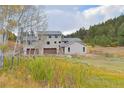 Two story home with an attached three car garage sits on a grassy lot with trees and foliage at 20101 Spring Gulch Rd, Morrison, CO 80465