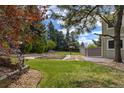 Lush backyard featuring a spacious lawn, mature trees, garden beds, and a peaceful outdoor setting at 6302 S Ivy Ct, Centennial, CO 80111