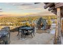 Outdoor patio with stone fireplace, mountain views, and dining set creates an inviting entertaining space at 142 Outpost Ln, Evergreen, CO 80439