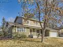 This home boasts a well-manicured lawn, a brick facade, a large tree, and an attached two car garage at 7388 S Lafayette W Cir, Centennial, CO 80122