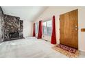 Bright living room with a stone fireplace, vaulted ceilings, neutral walls and carpeting, plus red curtains and wood front door at 16036 E Ithaca Pl # E, Aurora, CO 80013