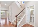 Hallway featuring hardwood floors, a staircase, and a view into a powder room at 3565 E 141St Dr, Thornton, CO 80602
