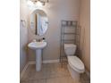 Cozy powder room features a pedestal sink, neutral paint, tile flooring, and modern shelving at 3565 E 141St Dr, Thornton, CO 80602