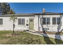 Charming white brick home featuring a well-kept front yard and a quaint olive front door at 3201 Albion St, Denver, CO 80207