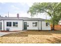 Charming white brick home with a well-manicured front yard and walkway leading to a green front door with the house number 3203 at 3201 Albion St, Denver, CO 80207