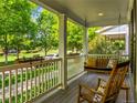 Relaxing covered front porch featuring a swing, rocking chairs, and a view of the lush green neighborhood at 7899 E 28Th Pl, Denver, CO 80238