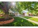 Charming home with lush green lawn and mature tree shading the front, creating a welcoming curb appeal at 8035 S Garfield Way, Centennial, CO 80122