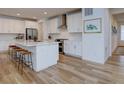 Spacious kitchen with stainless steel appliances, white cabinets, an island with bar stools, and modern light fixtures at 11246 Bellsong Ln, Littleton, CO 80125