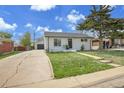 Quaint single-story home with a driveway leading to a detached garage and a vibrant green lawn at 7001 Alan Dr, Denver, CO 80221