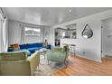 Cozy living room with hardwood floors, a blue couch, green chairs, and an open view of the kitchen at 7001 Alan Dr, Denver, CO 80221