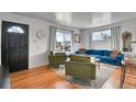 Inviting living room with hardwood floors, comfortable seating, natural light, and a black front door at 7001 Alan Dr, Denver, CO 80221