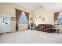 Bright living room featuring vaulted ceilings, large windows, and a comfortable seating area with a leather sofa at 11499 Kenton St, Commerce City, CO 80640