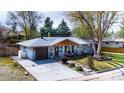Well-maintained single-story home featuring a gray brick exterior, tidy landscaping, and a wooden garage door at 6045 S Cook St, Centennial, CO 80121