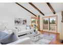 Inviting living room with hardwood floors, stone accents, exposed beams, and bright, natural light at 1340 Deerpath Trl, Franktown, CO 80116