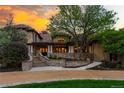 Stunning home with a stone exterior, beautiful landscaping, and a grand entrance at sunset at 45 Charlou Cir, Cherry Hills Village, CO 80111