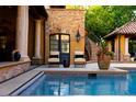 Outdoor pool with chairs, covered patio, and a staircase leading up to the next level of the home at 45 Charlou Cir, Cherry Hills Village, CO 80111