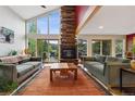 Inviting living room with a stone fireplace, high ceilings, ample natural light, and outside access at 4230 S Meadow Brook Ln, Evergreen, CO 80439