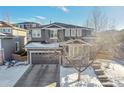 Two-story home with gray siding, stone accents, and a snow-covered yard at 10551 Applebrook Cir, Highlands Ranch, CO 80130