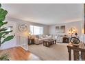 Bright living room with a large couch, wood floors, and a big window with natural light at 8262 Otis Ct, Arvada, CO 80003