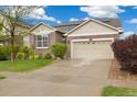 Beautiful front exterior showcasing a brick facade, green lawn, and a driveway leading to a two-car garage at 25811 E Archer Ave, Aurora, CO 80018