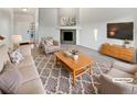 Living room with neutral tones featuring modern decor, a fireplace, plush seating, and a stylish area rug at 25952 E 5Th Pl, Aurora, CO 80018