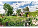 A beautiful yard featuring a well-kept lawn, mature trees, decorative fence and manicured greenery surrounding the home at 1060 S Eaton St, Lakewood, CO 80226