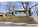 Inviting home exterior with white brick, black trim, mature tree, and detached garage at 5060 S Fox St, Englewood, CO 80110