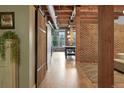 Hallway with exposed brick wall, wood flooring, a sliding barn door, and view to the main living area at 2955 Inca St # 2D, Denver, CO 80202