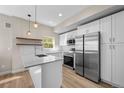 Contemporary kitchen featuring white cabinets, stainless steel appliances, quartz countertops, and modern lighting at 2140 S Ash St # 105, Denver, CO 80222