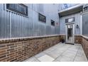 Modern outdoor courtyard with brick accent wall, tiled patio, and sleek corrugated metal wall at 4144 Tennyson St # 212, Denver, CO 80212