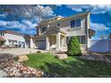 Beautifully landscaped front yard with lush lawn, decorative rock accents, and a mature shade tree at 21229 E 50Th Ave, Denver, CO 80249