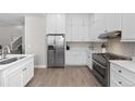 Bright kitchen with white cabinets, stainless steel appliances, gas range, and wood floors at 12214 Stone Timber Ct, Parker, CO 80134